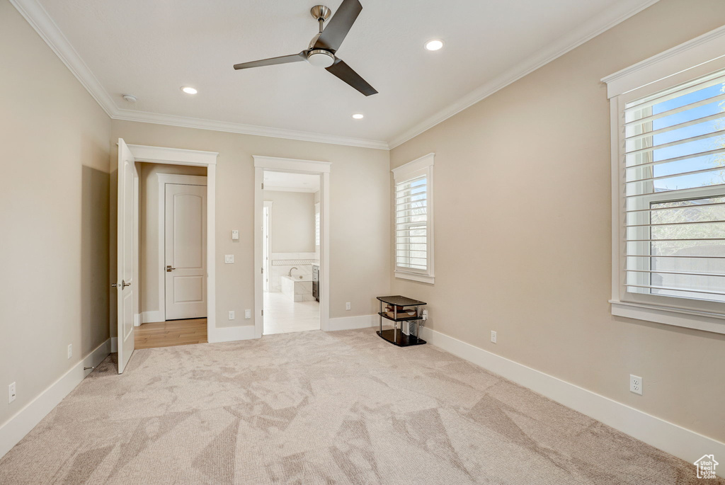 Unfurnished bedroom featuring ornamental molding, light carpet, ceiling fan, and multiple windows
