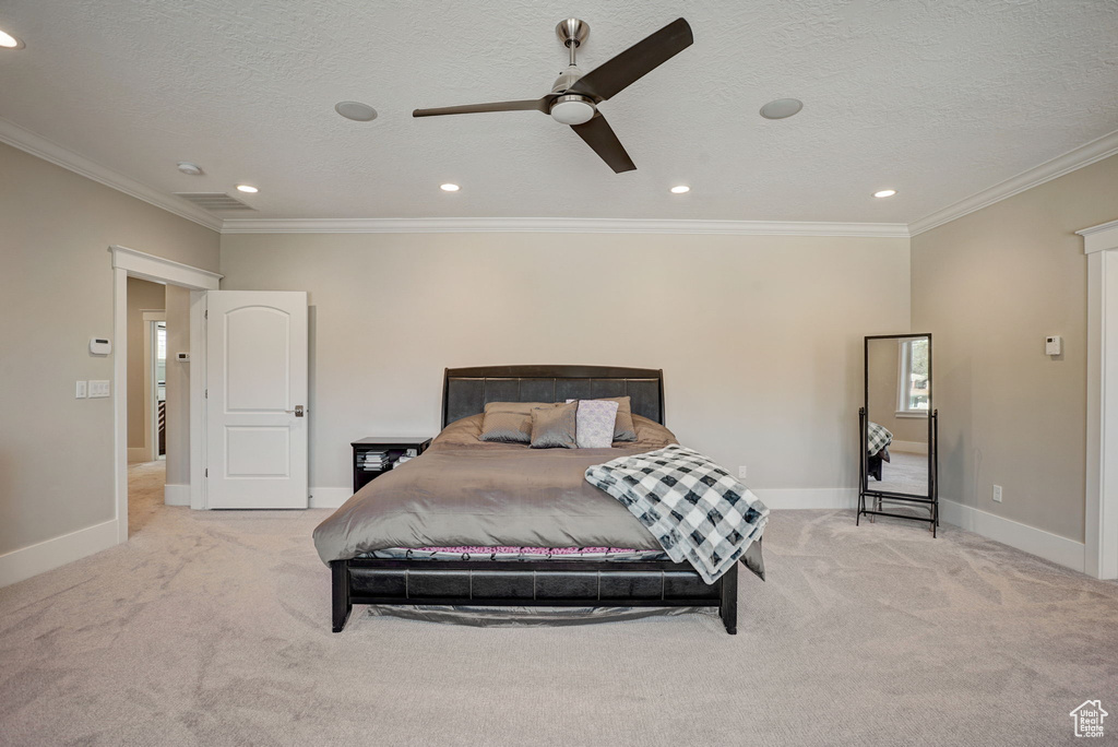 Bedroom featuring light colored carpet, ceiling fan, ornamental molding, and a textured ceiling