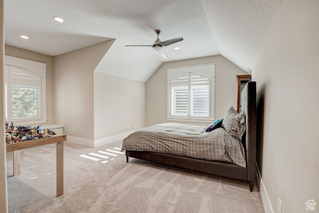 Carpeted bedroom with vaulted ceiling, ceiling fan, a textured ceiling, and multiple windows