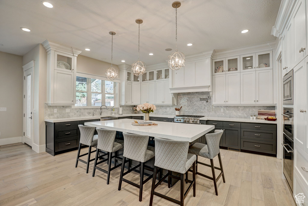 Kitchen featuring a kitchen island, tasteful backsplash, hanging light fixtures, and white cabinetry