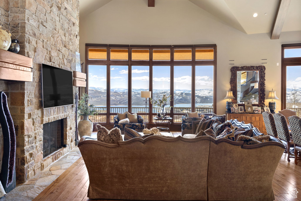 Living room featuring beamed ceiling, wood-type flooring, a mountain view, and a stone fireplace