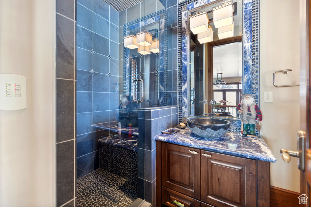 Bathroom featuring tiled shower and vanity