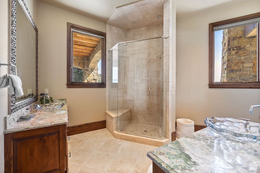 Bathroom with a shower with door, tile floors, and large vanity