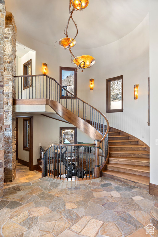 Staircase featuring plenty of natural light, a towering ceiling, and a chandelier
