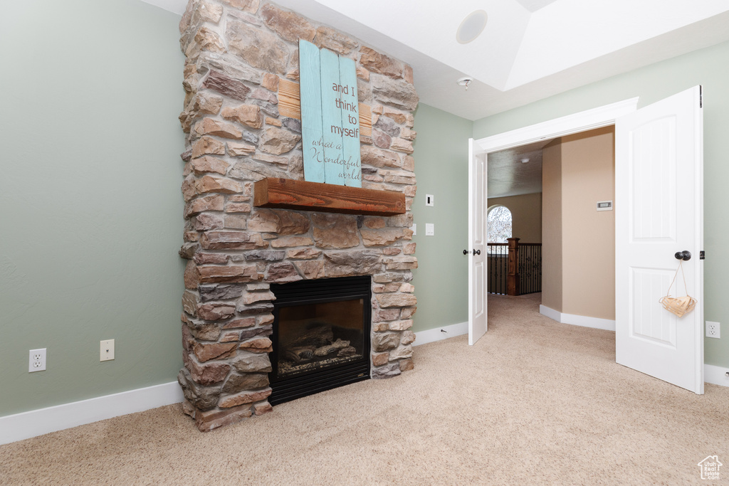 Unfurnished living room featuring a stone fireplace and light carpet