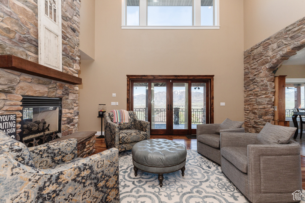 Living room with plenty of natural light, light hardwood / wood-style floors, a stone fireplace, and a high ceiling