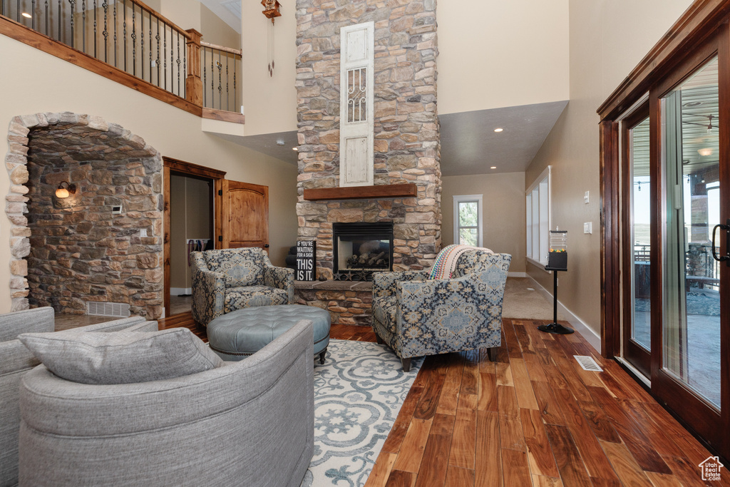 Living room with a stone fireplace, dark wood-type flooring, and a towering ceiling