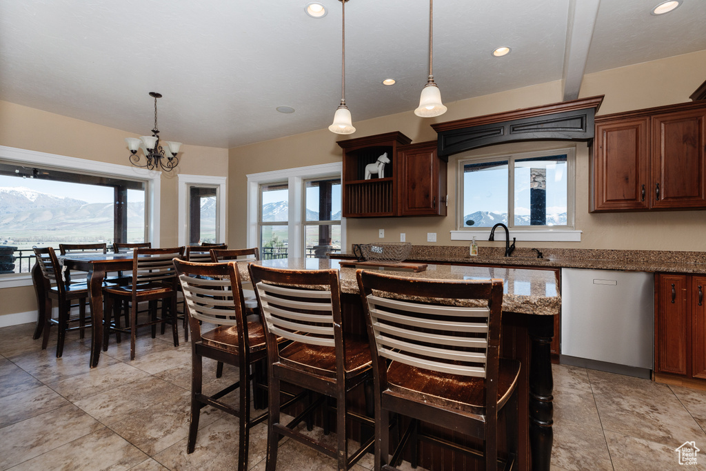 Kitchen featuring decorative light fixtures, light stone counters, light tile floors, and a breakfast bar