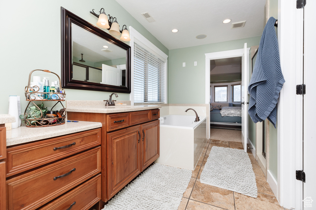 Bathroom with a tub, vanity with extensive cabinet space, and tile flooring