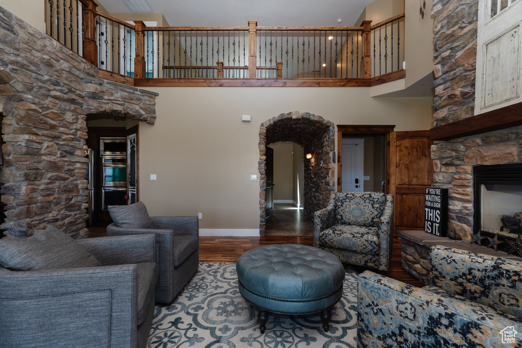 Living room with a stone fireplace, dark hardwood / wood-style floors, and a high ceiling