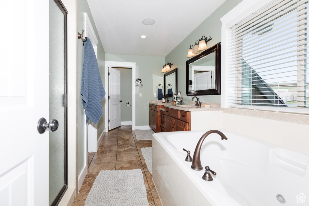 Bathroom featuring a washtub, tile flooring, and vanity