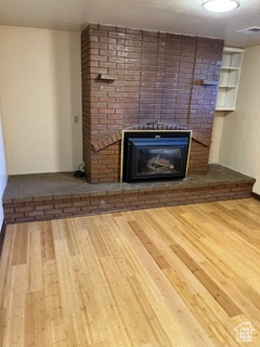 Unfurnished living room with hardwood / wood-style flooring, brick wall, and a fireplace