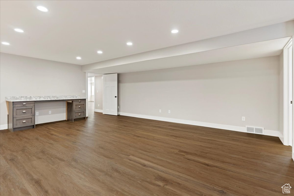 Basement with built in desk and dark hardwood / wood-style flooring