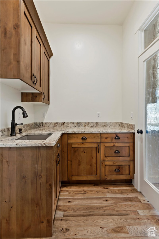 Kitchen featuring sink, light hardwood / wood-style flooring, and light stone counters