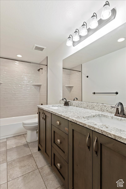 Full bathroom with tile floors, tiled shower / bath, toilet, and double vanity