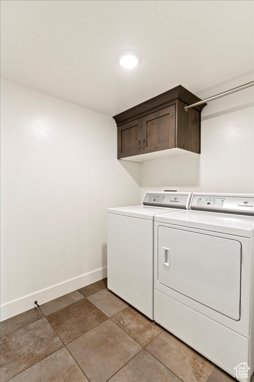 Clothes washing area with cabinets, independent washer and dryer, and light tile flooring