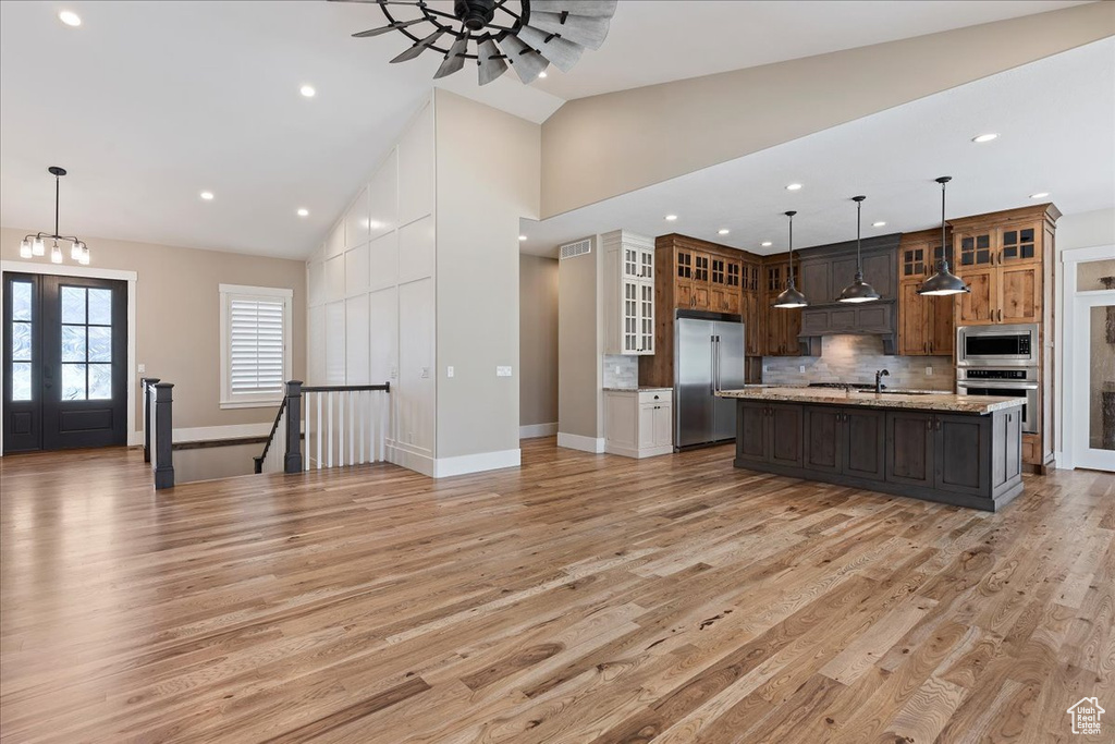 Kitchen featuring a kitchen island with sink, appliances with stainless steel finishes, light hardwood / wood-style floors, and dark brown cabinets