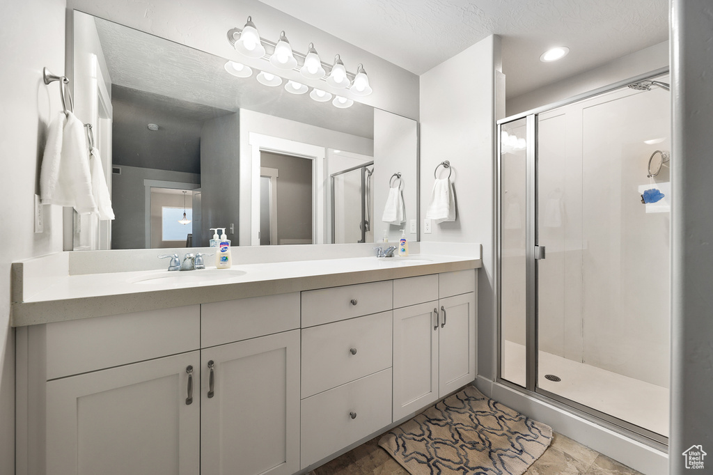 Bathroom featuring walk in shower, dual vanity, and tile flooring