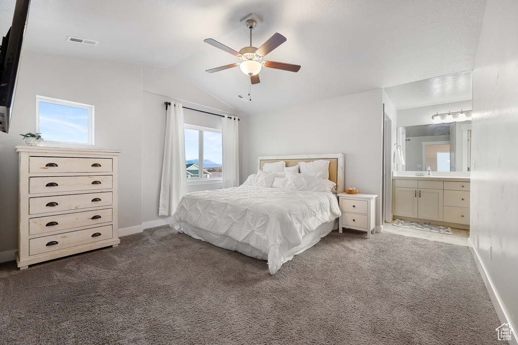 Bedroom with carpet floors, connected bathroom, ceiling fan, and vaulted ceiling