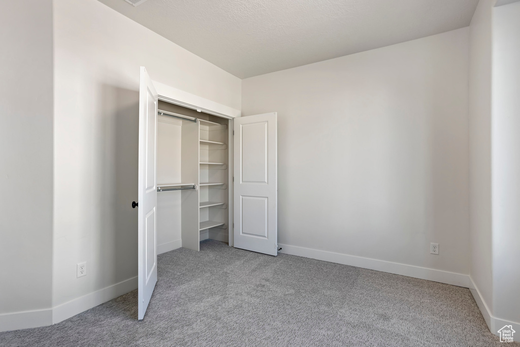 Unfurnished bedroom featuring light colored carpet and a closet