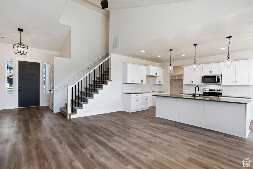 Kitchen featuring white cabinets, stainless steel appliances, dark hardwood / wood-style flooring, and hanging light fixtures