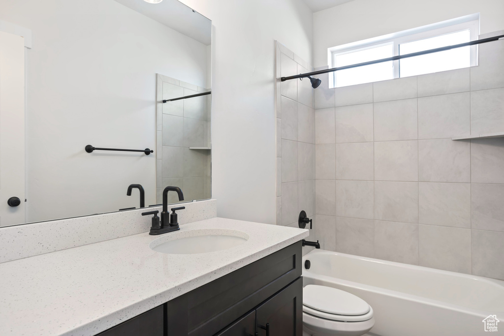 Full bathroom featuring tiled shower / bath combo, vanity, and toilet