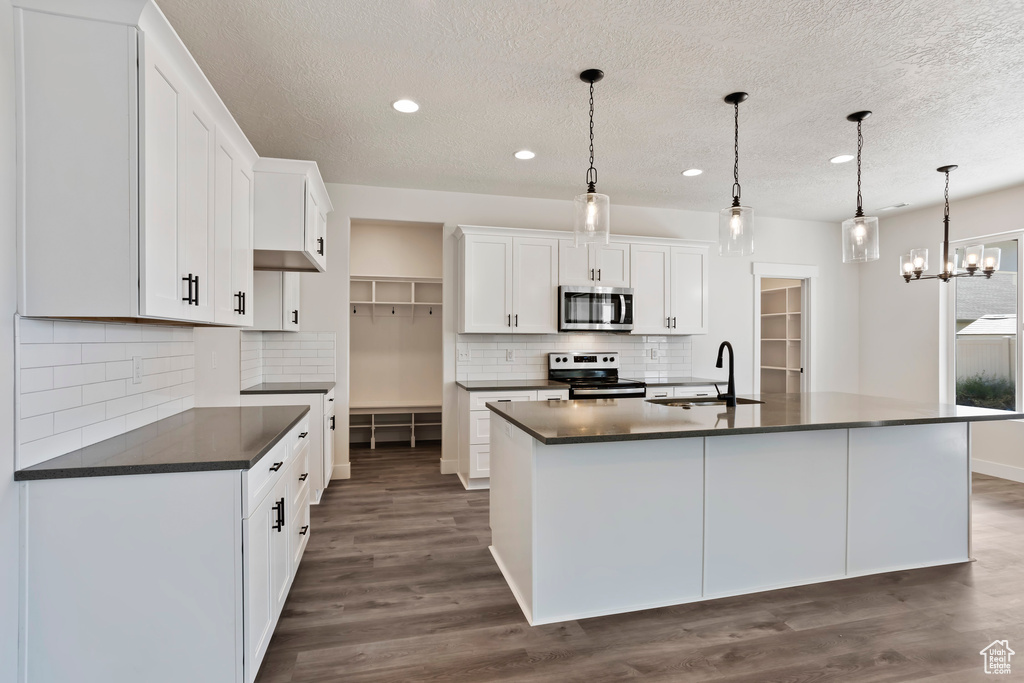 Kitchen featuring appliances with stainless steel finishes, dark hardwood / wood-style floors, tasteful backsplash, white cabinets, and sink