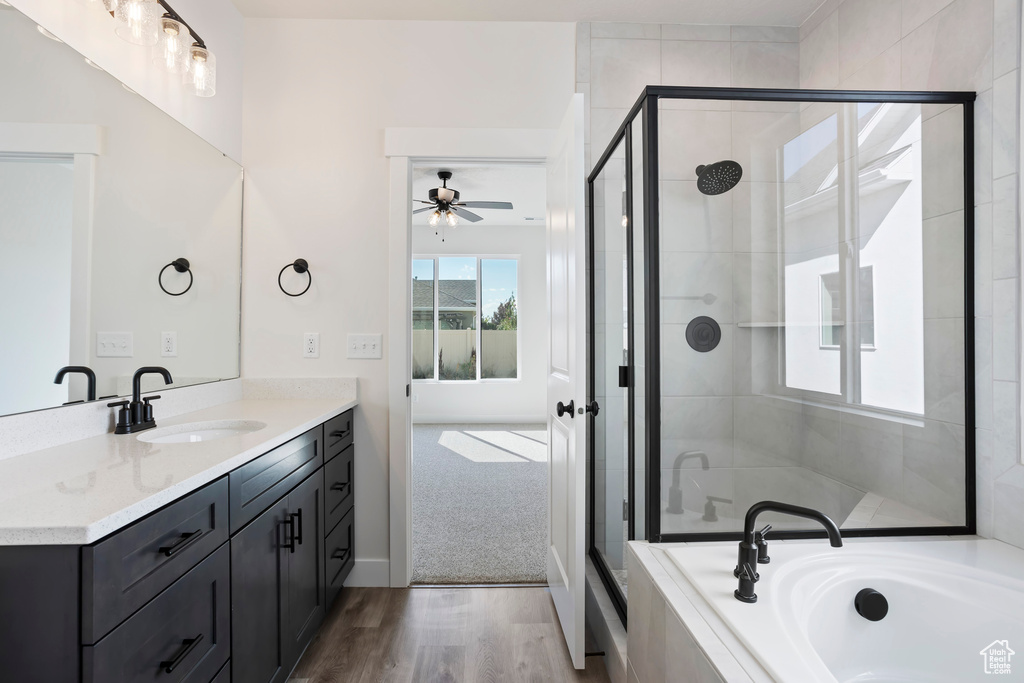 Bathroom featuring wood-type flooring, ceiling fan, vanity, and shower with separate bathtub