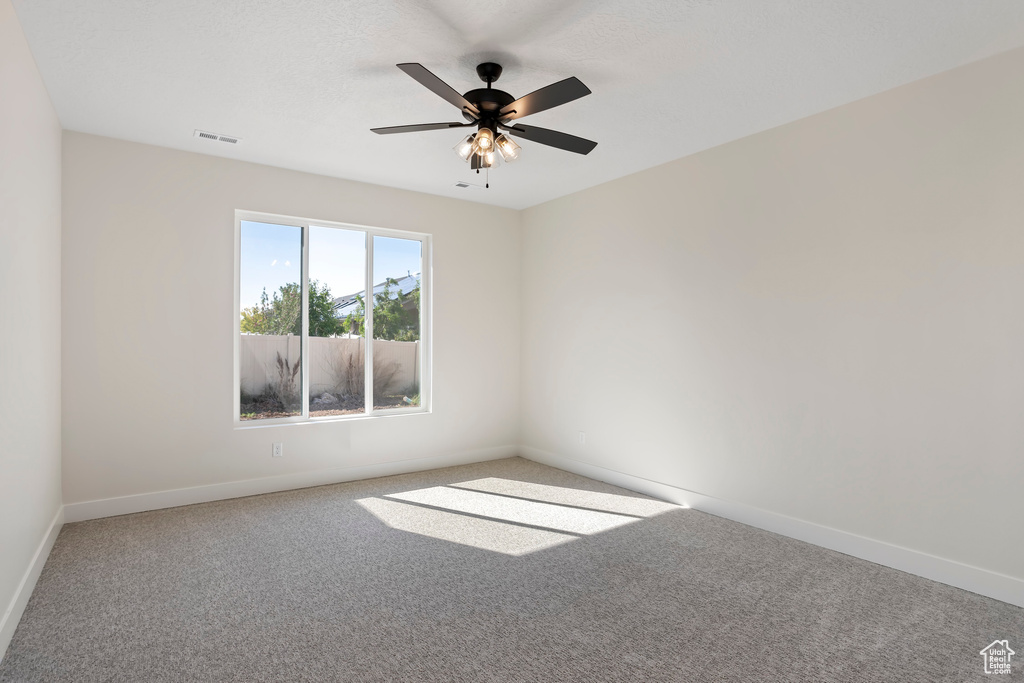 Empty room with light colored carpet and ceiling fan