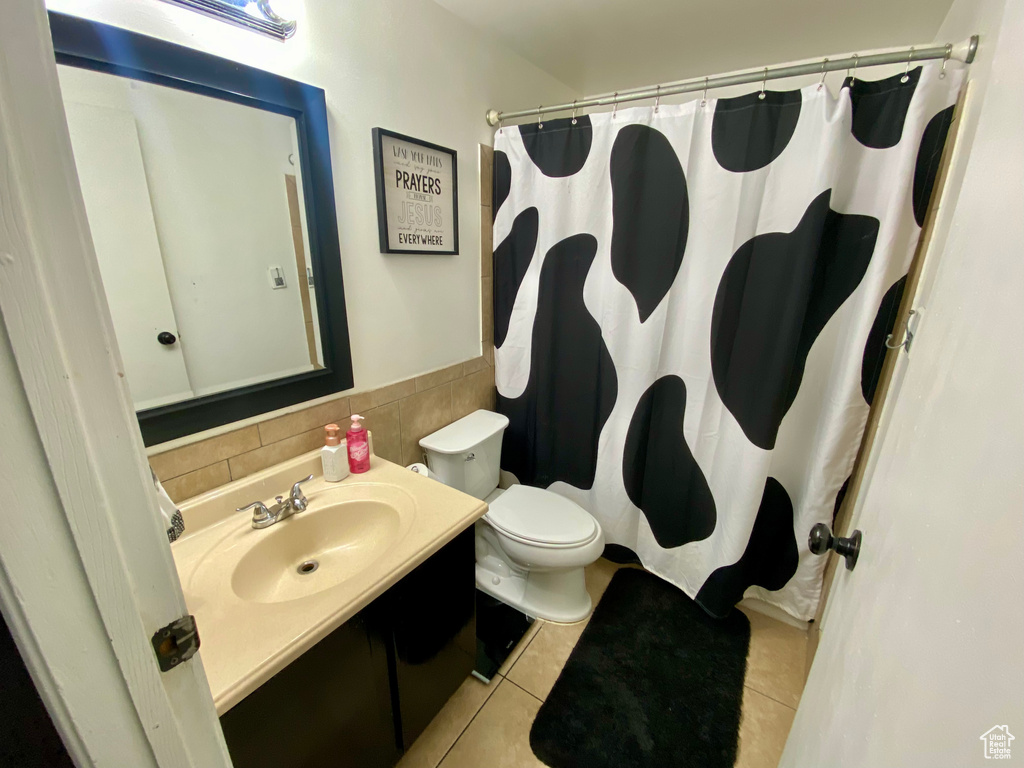 Bathroom featuring backsplash, oversized vanity, toilet, and tile flooring