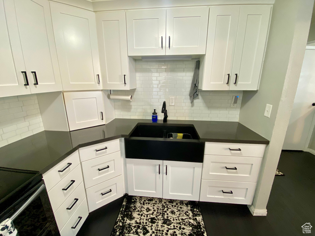 Kitchen featuring backsplash, dark hardwood / wood-style flooring, and white cabinetry