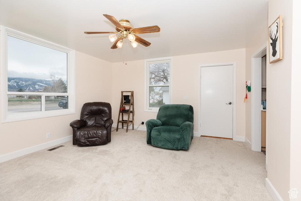 Living area with light carpet and ceiling fan