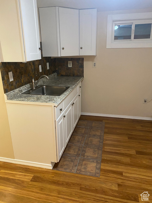 Kitchen featuring white cabinets, sink, backsplash, and dark wood-type flooring