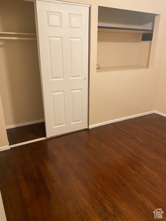 Unfurnished bedroom with a closet and dark hardwood / wood-style flooring