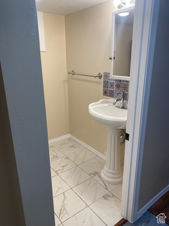 Bathroom with tasteful backsplash, tile flooring, and a textured ceiling