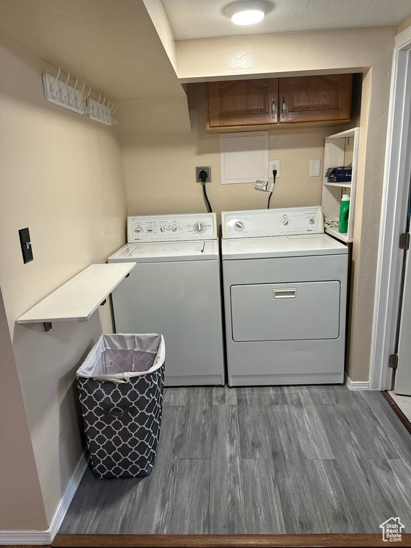 Laundry area featuring hookup for an electric dryer, dark hardwood / wood-style flooring, cabinets, and washing machine and clothes dryer