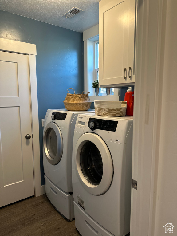 Clothes washing area featuring independent washer and dryer, cabinets, dark wood-type flooring, and a textured ceiling