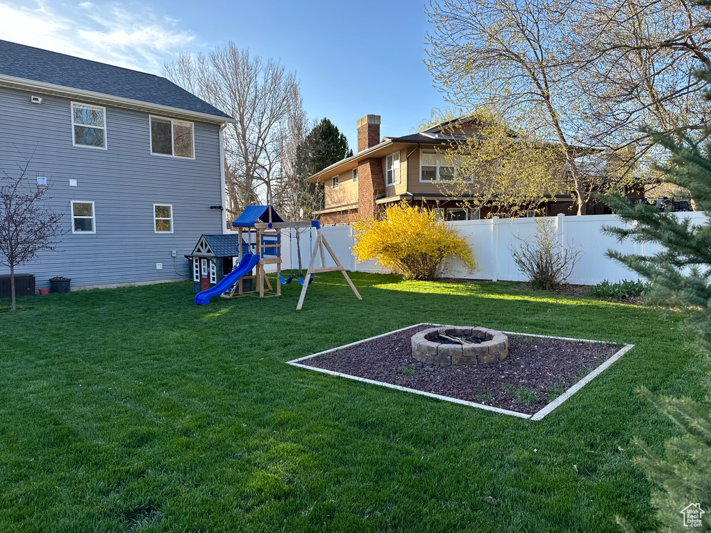View of yard featuring a playground, a fire pit, and central air condition unit