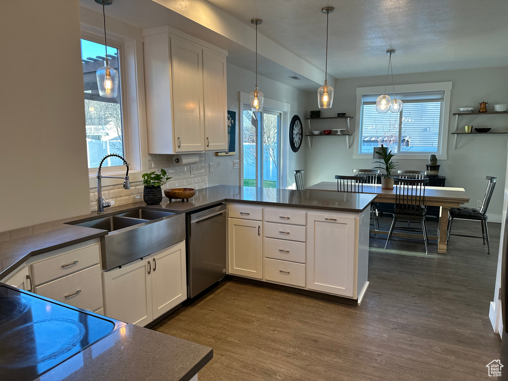 Kitchen with dishwasher, kitchen peninsula, backsplash, and dark wood-type flooring