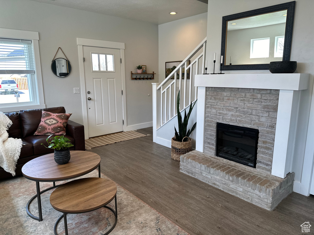 Living room with dark wood-type flooring and a brick fireplace