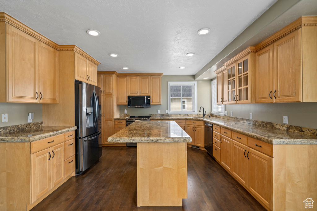 Kitchen featuring a center island, dark hardwood / wood-style flooring, appliances with stainless steel finishes, sink, and light stone counters