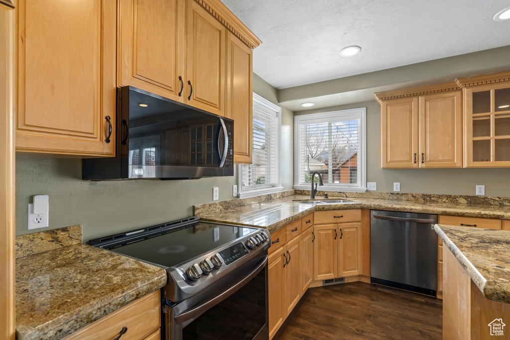 Kitchen featuring appliances with stainless steel finishes, light brown cabinets, sink, dark hardwood / wood-style floors, and light stone countertops