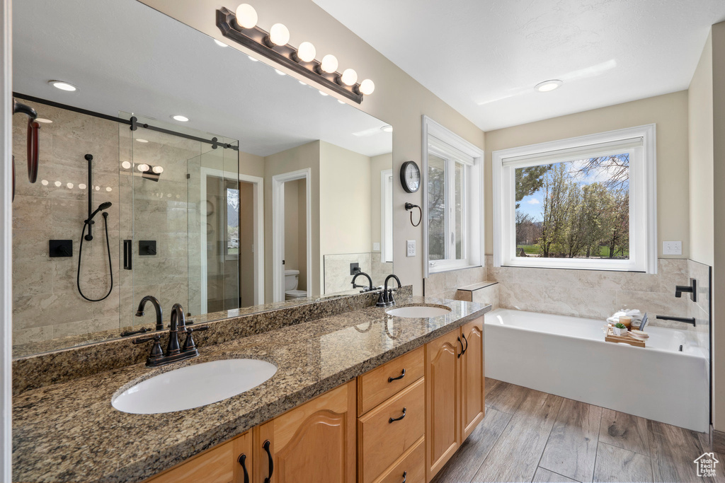 Full bathroom featuring hardwood / wood-style floors, separate shower and tub, toilet, and double sink vanity