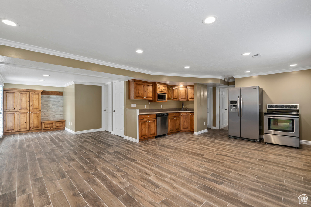 Kitchen with dark hardwood / wood-style floors, sink, stainless steel appliances, and crown molding