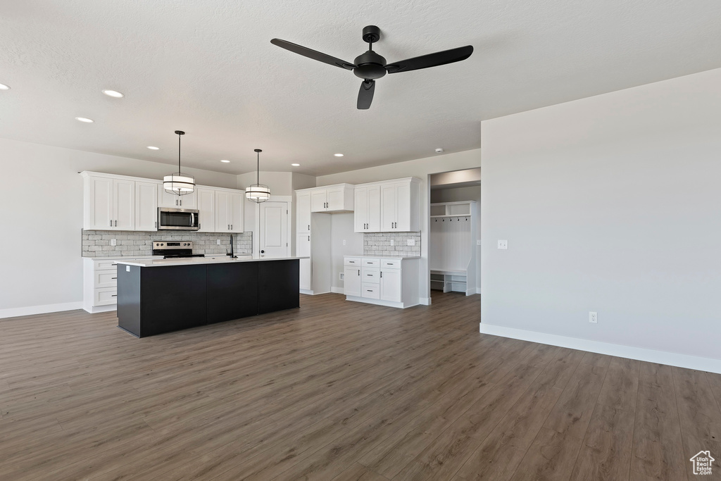 Kitchen with a center island with sink, white cabinetry, stainless steel appliances, and dark hardwood / wood-style floors