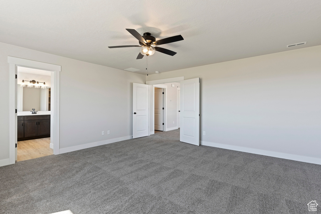 Unfurnished bedroom featuring light colored carpet, ceiling fan, and ensuite bathroom