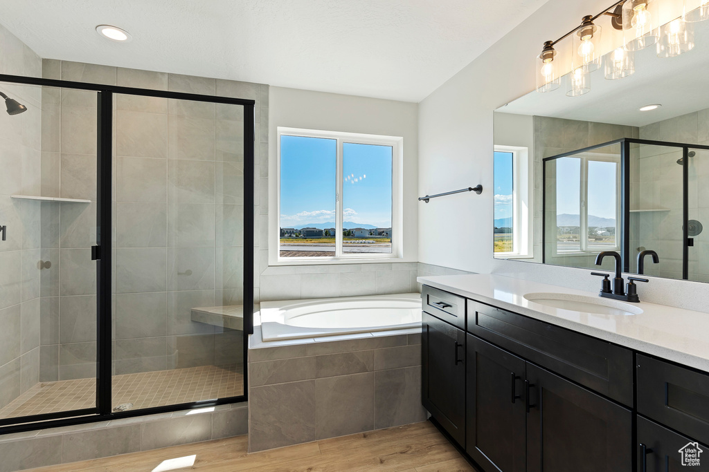 Bathroom with a healthy amount of sunlight, wood-type flooring, vanity, and separate shower and tub