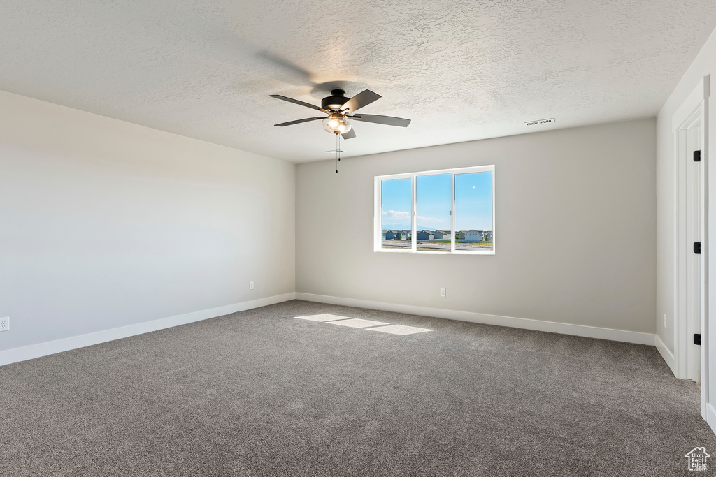 Empty room featuring a textured ceiling, ceiling fan, and carpet floors