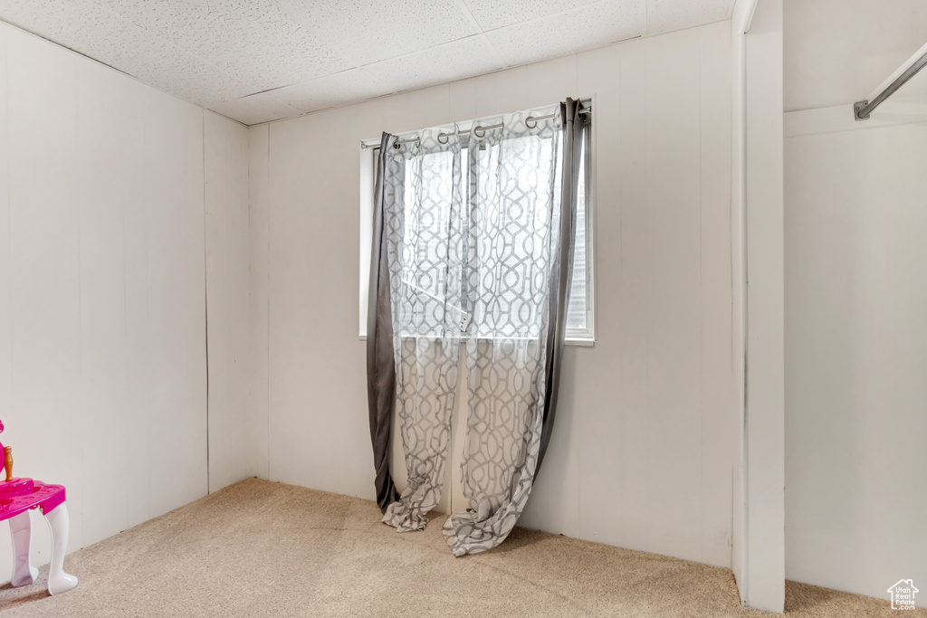 Empty room featuring light colored carpet and a paneled ceiling