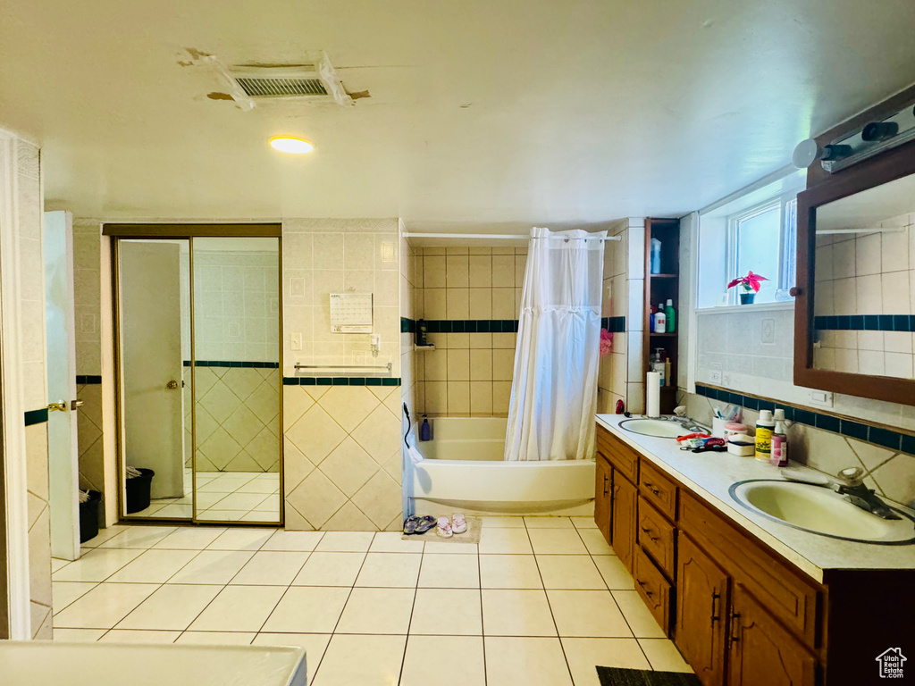 Bathroom featuring tile flooring, tile walls, and dual vanity